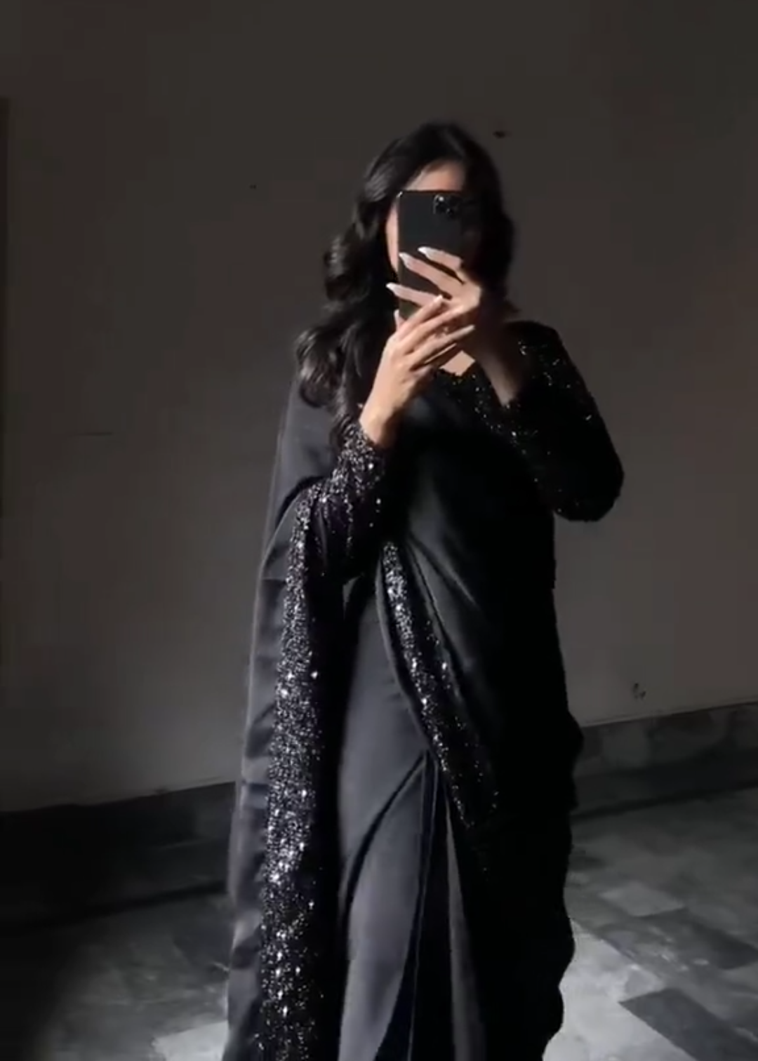 Person wearing a black traditional outfit with a plain background